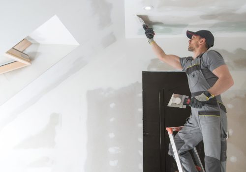 Finishing and Patching Drywall Walls by Caucasian Remodeler in His 30s. Construction Industry.